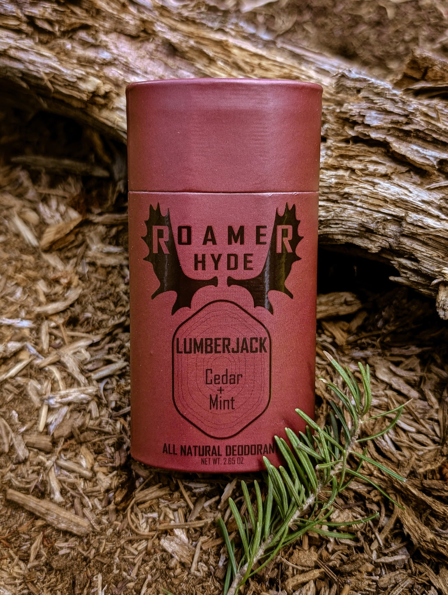 Red deodorant can labeled 'Roamer Hyde Lumberjack Cedar Mint' on a wooden background